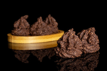 Group of five whole homemade brown coconut cocoa biscuit on bamboo coaster isolated on black glass