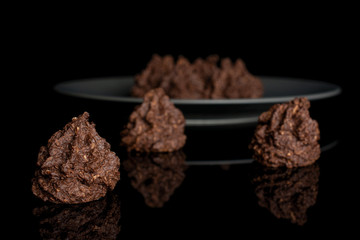 Group of seven whole homemade brown coconut cocoa biscuit on gray ceramic plate isolated on black glass