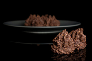 Group of six whole homemade brown coconut cocoa biscuit on gray ceramic plate isolated on black glass