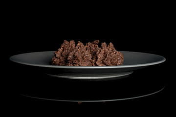 Group of four whole homemade brown coconut cocoa biscuit on gray ceramic plate isolated on black glass