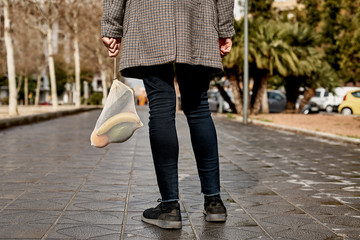 man carrying a mesh bag full of fruit and vegs.