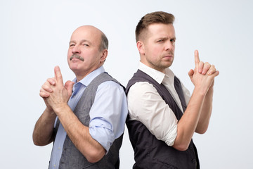 Two caucasian businessman doing a gun gesture getting ready to shoot and acting like a secret agent