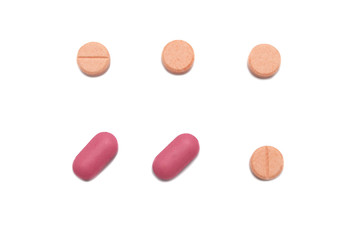 Prescription drugs or medicine of different colors between orange and pink colors isolated on white background.