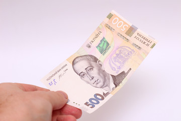 A banknote of 500 hryvnia in a male hand on a white background. Giving a bribe in Ukraine. European money exchange. Ukraine currency