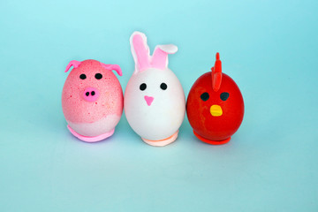 Easter holiday, a handmade egg made by a child in the form of a rabbit , chicken  and pig against a blue background.