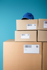 Cap on stacked cardboard boxes with qr and barecodes isolated on blue