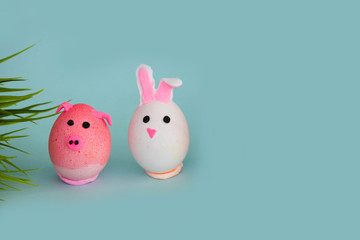 Easter holiday, a handmade egg made by a child in the form of a rabbit and pig against a blue background.