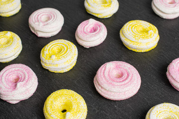 Lot of whole pink and yellow sweet meringue on grey stone