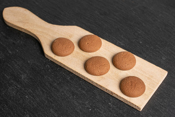 Group of five whole sweet brown chocolate sponge biscuit on small wooden cutting board on grey stone
