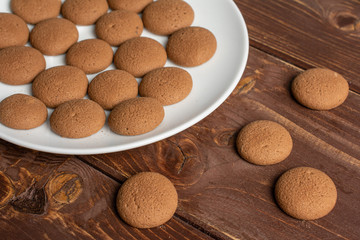 Lot of whole sweet brown chocolate sponge biscuit on white ceramic plate on brown wood