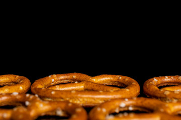 Lot of whole salty brown pretzel macro isolated on black glass