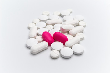 Prescription drugs, pills and tablets of different colors between white and pink tablets . On a white background. Selective focus.