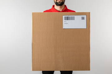 Cropped view of courier holding package with barcode and qr code on card isolated on grey