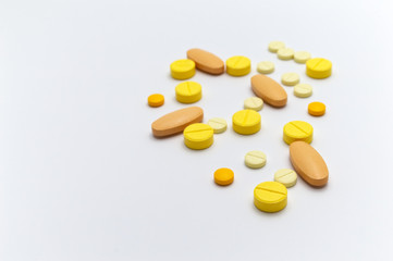Prescription drugs or medicine pills and vitamin C tablets of yellow colors shades. On white background. Selective focus and Copy space.