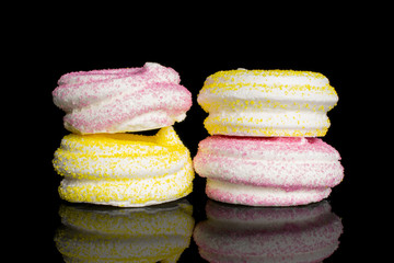 Group of four whole pink and yellow sweet meringue isolated on black glass