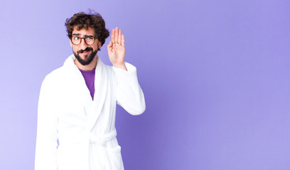 young bearded man wearing bathrobe looking serious and curious, listening, trying to hear a secret...