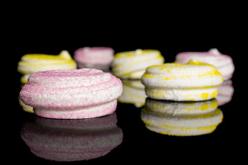 Group of six whole pink and yellow sweet meringue isolated on black glass