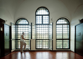 Prisoner in jail looking outside through large windows