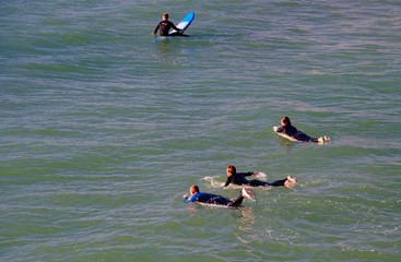 Surfers on the wooden pier of Pismo Beach in California