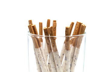 Chocolate biscuit stick coated with milk flavour confectionery and crushed cookies and cream taste in the glass isolated on white background.