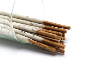 Chocolate biscuit stick coated with milk flavour confectionery and crushed cookies and cream taste in the glass isolated on white background.