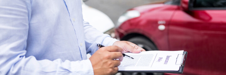Insurance agent writing on clipboard while examining car after accident claim being assessed and...