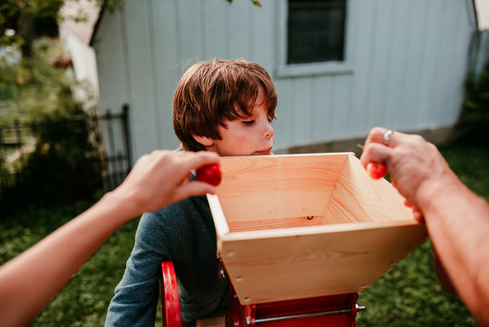 Father and two children pressing apples to make cider, USA