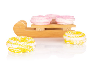 Group of five whole pink and yellow sweet meringue with wooden sledge isolated on white background