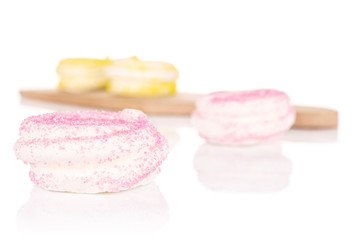 Group of four whole pink and yellow sweet meringue on small wooden cutting board isolated on white background