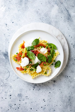 Italian pasta mafalde with green peas, prosciutto, burrata,  and spinach
