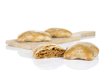 Group of three whole one half of sweet brown gingerbread on small wooden cutting board isolated on white background