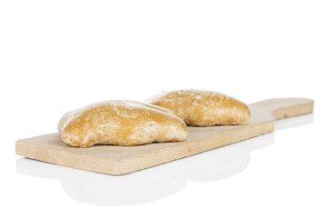 Group of two whole sweet brown gingerbread on small wooden cutting board isolated on white background