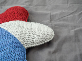 Closeup hand made multicolored yarn knitted pillow in the shape of a starfish on a gray background. Natural materials for the interior. Chemical free textile