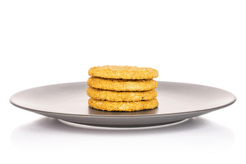Group of four whole sweet golden oat cookie on gray ceramic plate isolated on white background