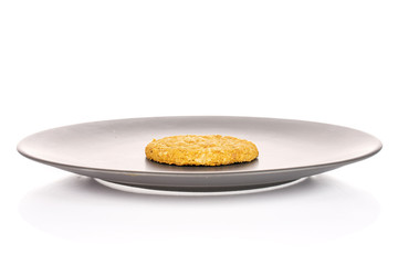 One whole sweet golden oat cookie on gray ceramic plate isolated on white background