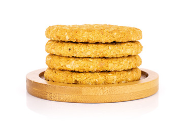 Group of four whole sweet golden oat cookie on bamboo coaster isolated on white background