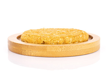 One whole sweet golden oat cookie on bamboo coaster isolated on white background