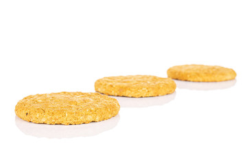 Group of three whole sweet golden oat cookie placed diagonally isolated on white background