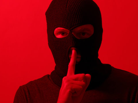 Man In A Balaclava Portrait, A Thief On A Red Background, Showing Sign Quieter.