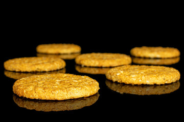 Group of six whole sweet golden oat cookie isolated on black glass