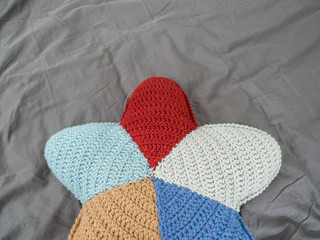Closeup hand made multicolored yarn knitted pillow in the shape of a starfish on a gray background. Natural materials for the interior. Chemical free textile
