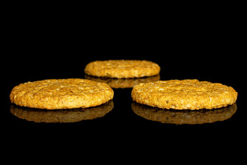 Group of three whole sweet golden oat cookie isolated on black glass