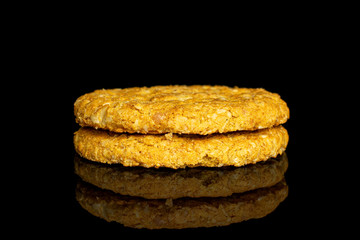 Group of two whole sweet golden oat cookie isolated on black glass