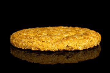 One whole sweet golden oat cookie isolated on black glass