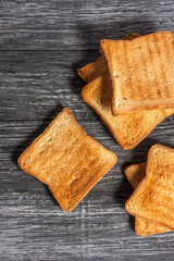 Several slices of toasted bread toasts on a wooden dark background