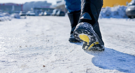 male or female winter boots walking on snowy sleet road