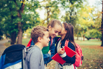 Positive kids whispering a secret each other in the ears.
