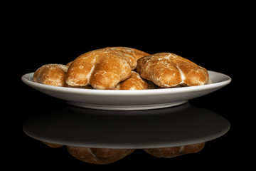 Group of five whole sweet brown gingerbread on white ceramic plate isolated on black glass