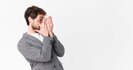 young crazy businessman feeling scared or embarrassed, peeking or spying with eyes half-covered...