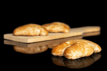 Group of three whole sweet brown gingerbread on small wooden cutting board isolated on black glass